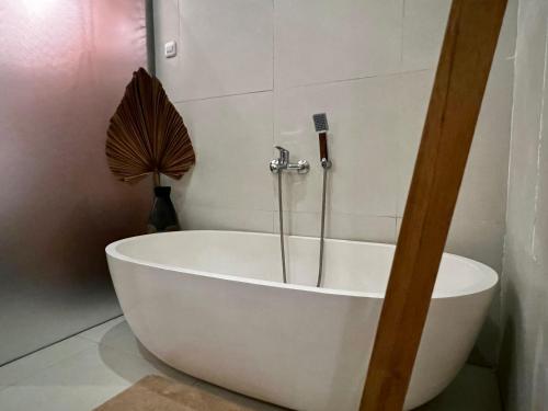 a white bath tub in a bathroom with a fan at Villa Sandhyā Tabanan in Tabanan
