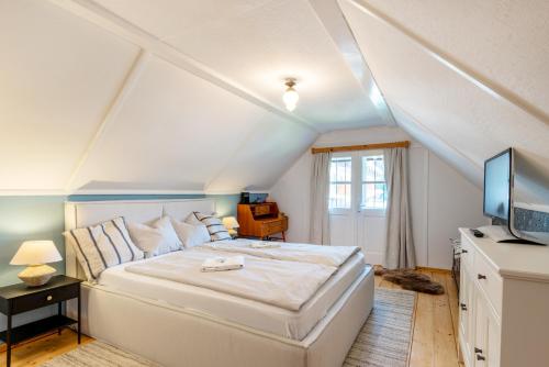 a bedroom with a large white bed and a television at Cottage Hohe Tauern in Mallnitz