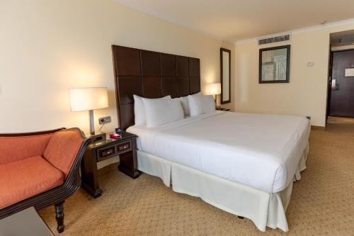 a hotel room with a large bed and a chair at Dominican Fiesta Hotel in Santo Domingo