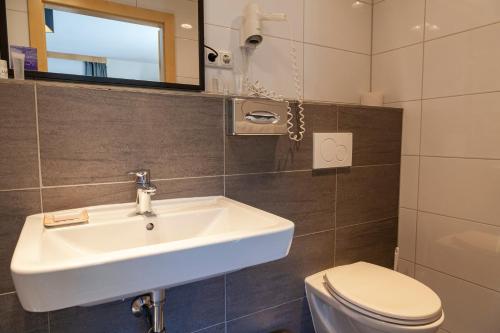 a bathroom with a sink and a toilet at Berghotel TheLounge in Berwang