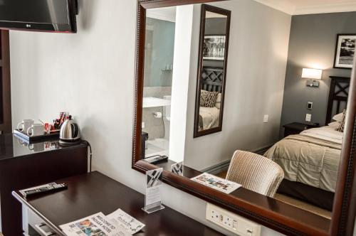 a hotel room with a desk and a mirror at Indaba Hotel, Spa & Conference Center in Johannesburg