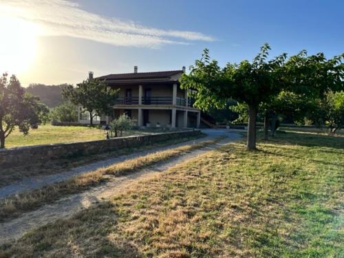 une maison avec un arbre devant un champ dans l'établissement Jolie maison à louer dans les Cévennes, à Saint-Christol-lès-Alès