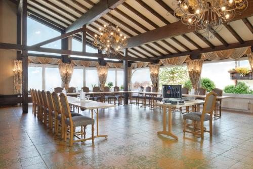 a dining room with tables and chairs and a chandelier at Hotel Zum weißen Stein in Kirchen