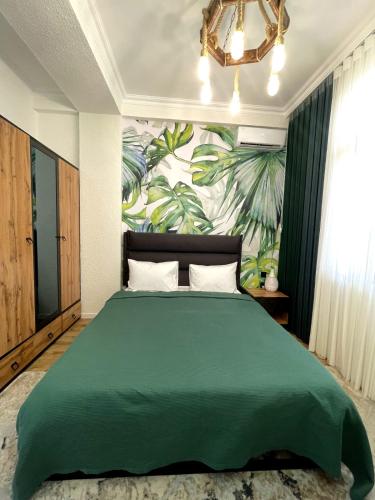 a bedroom with a green bed with a tropical wallpaper at Style Home Buzovna in Baku
