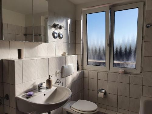 a bathroom with a sink and a toilet and two windows at FEWODAYs Ferienwohnung in Sassnitz - Ruegen in Sassnitz