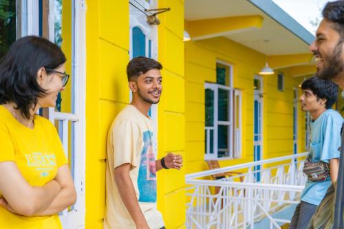 a group of people standing outside of a yellow house at Whoopers Hostel Bir in Bīr