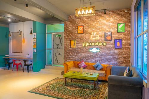 a living room with a couch and a brick wall at Whoopers Hostel Bir in Bīr