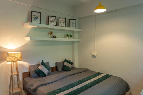 a bedroom with a bed with green and white pillows at Whoopers Hostel Bir in Bīr