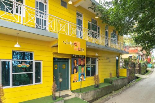 a yellow building with a balcony on a street at Whoopers Hostel Bir in Bīr