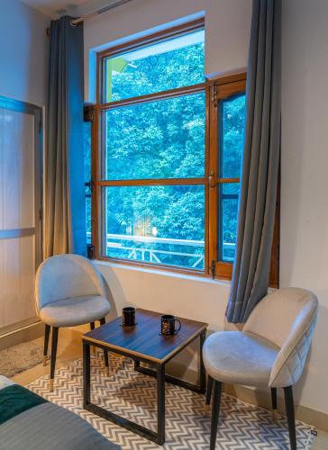 a bedroom with two chairs and a table and a window at Whoopers Hostel Bir in Bīr