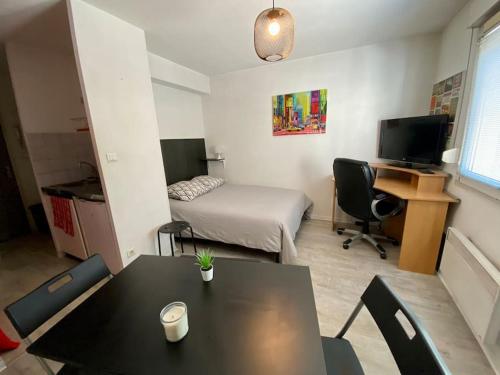 a small room with a table and a bed and a desk at Studio le République in Dijon