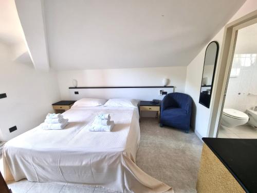a bedroom with a large white bed and a blue chair at Hotel Garden Bocca di Magra in Bocca di Magra