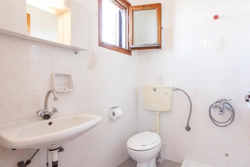 een witte badkamer met een toilet en een wastafel bij Platanakia in Skopelos Town