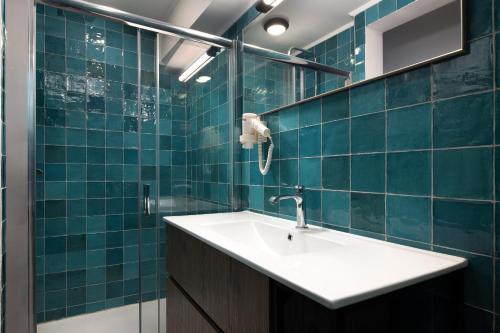a bathroom with a sink and blue tiled walls at The City Gem Urban Apt. in Rhodes Town