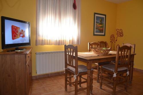 a dining room with a table and chairs and a television at Apartamentos El Prado in Valbona
