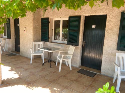 d'une terrasse avec des chaises, une table et des fenêtres. dans l'établissement Les Lodges de la Plage U Dragulinu, à Sari-Solenzara