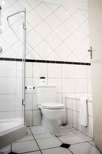 a white bathroom with a toilet and a shower at Indaba Hotel, Spa & Conference Center in Johannesburg