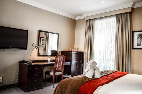 a hotel room with a teddy bear sitting on a bed at Indaba Hotel, Spa & Conference Center in Johannesburg