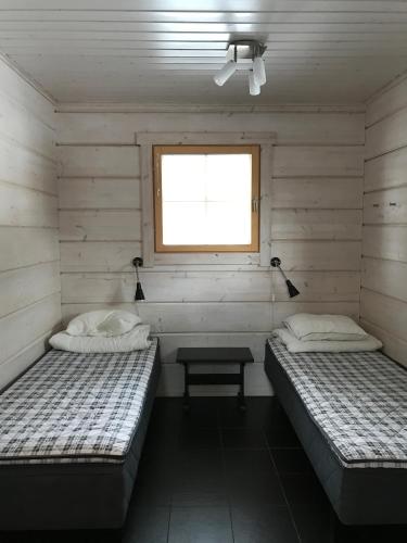 two beds in a room with a window at Villa Tumppu in Jämsä