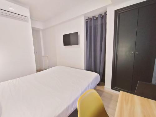 a bedroom with a white bed and a yellow chair at Hostal Carmen by gaiarooms in Salamanca