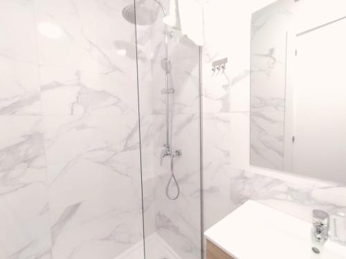 a white bathroom with a shower and a sink at Hostal Carmen by gaiarooms in Salamanca