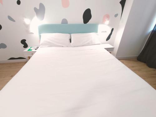 a bedroom with a white bed with a blue headboard at Hostal Carmen by gaiarooms in Salamanca