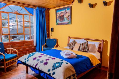 a bedroom with a bed with blue chairs and a window at Hotel y Spa Isla de Baños in Baños
