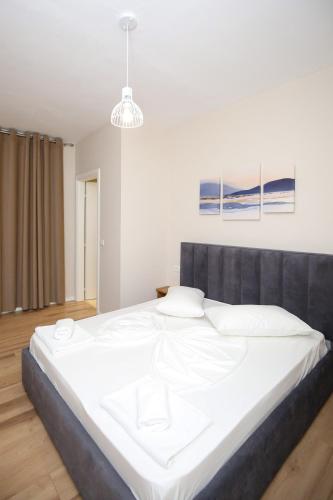 a large white bed in a bedroom with a light at Hotel Amantia in Orikum