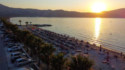 a beach with a lot of umbrellas and cars at Hotel Amantia in Orikum