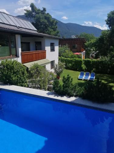 a pool with two blue chairs and a house at Haus Thomas in Telfs