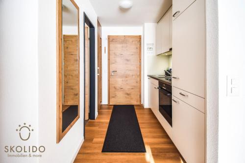 a hallway leading to a kitchen with a wooden door at Haus Camillo in Saas-Fee