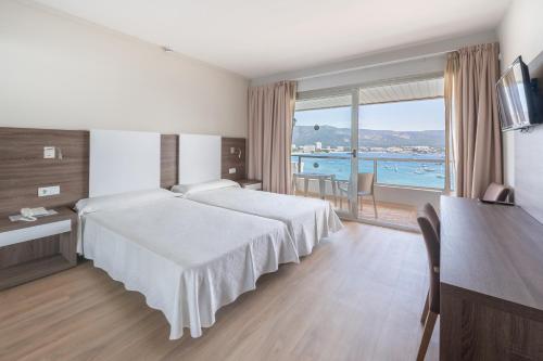 a hotel room with two beds and a view of the ocean at Seramar Hotel Comodoro Playa in Palmanova