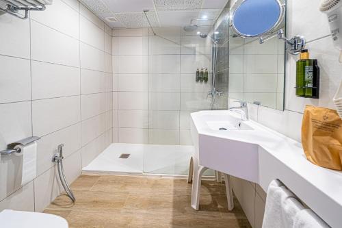 a white bathroom with a sink and a shower at Seramar Hotel Comodoro Playa in Palmanova