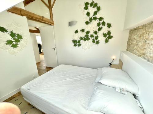 a bedroom with a white bed with plants on the wall at Villa de charme. Port. Plage. 4 km de Carnac. in La Trinité-sur-Mer