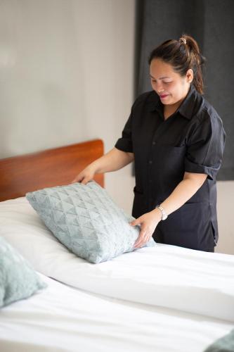 a woman putting a pillow on top of a bed at Gardermoen Hotel Bed & Breakfast in Gardermoen