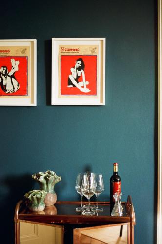 a table with wine glasses and pictures on a wall at Signau House & Garden Boutique Hotel Zürich in Zürich