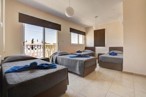 a hotel room with three beds and a balcony at Villa Nissi Gold in Ayia Napa
