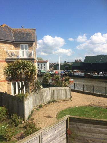a house with a fence in front of a river at Faversham Creekside Bed and Breakfast in Faversham