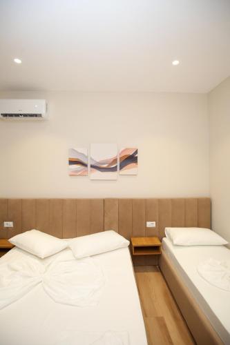 a bedroom with two beds and a painting on the wall at Hotel Amantia in Orikum