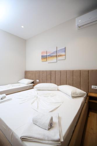 two beds in a room with white sheets at Hotel Amantia in Orikum