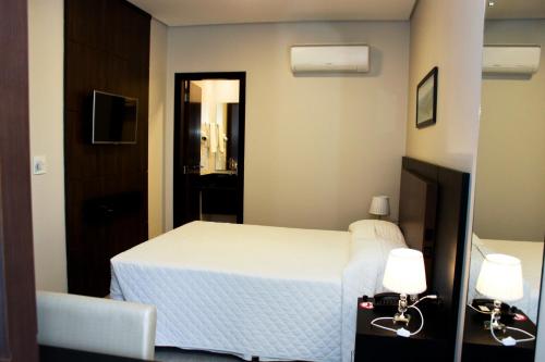 a bedroom with a white bed and a mirror at Blue Hill Hotel in Timbó