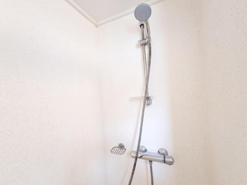 a shower with a shower head in a bathroom at Chalet BG03 direct achter de duinen! in Biggekerke