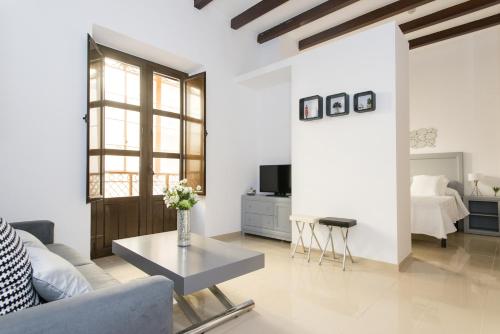 - un salon avec un canapé et une table dans l'établissement Apartamentos Plaza Nueva, à Séville