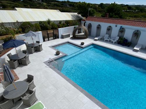 a swimming pool with chairs and tables next to a building at Beau Vallon Holiday Apartments in St Pierre du Bois