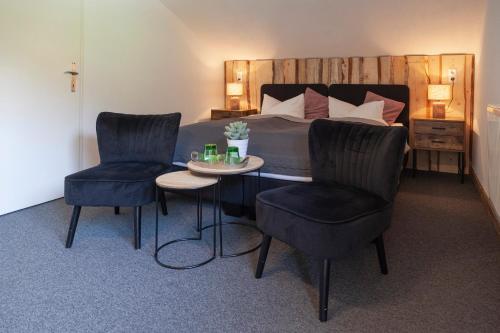 a bedroom with a bed and two chairs and a table at Berghotel TheLounge in Berwang