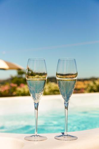 two wine glasses sitting on a table next to a pool at Tenuta Borgo Santa Cecilia in Gubbio