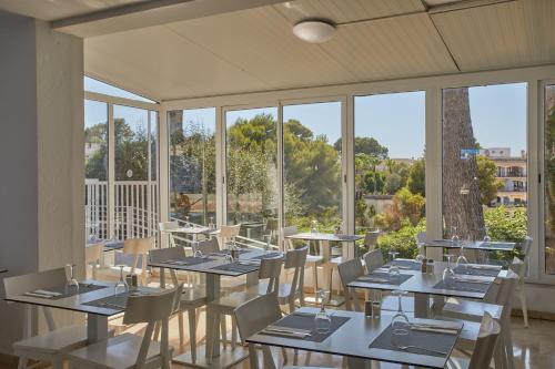 a dining room with tables and chairs and windows at JS Paradise Sport - Adults Only in El Arenal