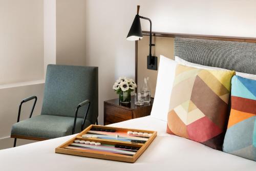 a tray of colored pencils on a bed with a chair at Hotel Seville NoMad - The Unbound Collection by Hyatt in New York