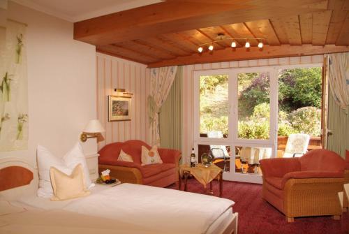 a bedroom with a bed and two chairs and a window at Hotel Zum weißen Stein in Kirchen