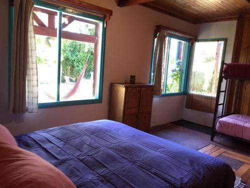 a bedroom with a bed and two windows at Hostel Raíz in Pucón